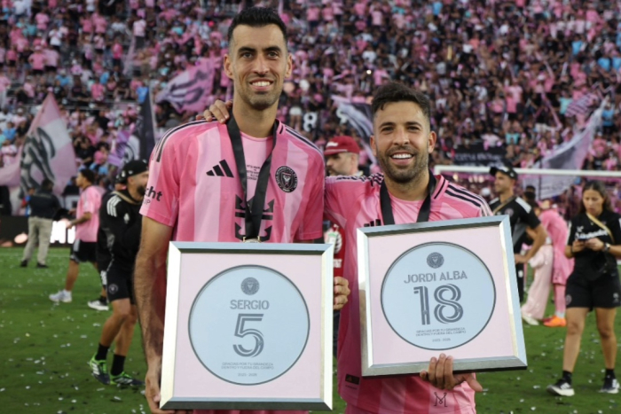 Jugadores del Inter Miami posan en la cancha con reconocimientos enmarcados, celebrando su trayectoria ante un estadio lleno de aficionados.