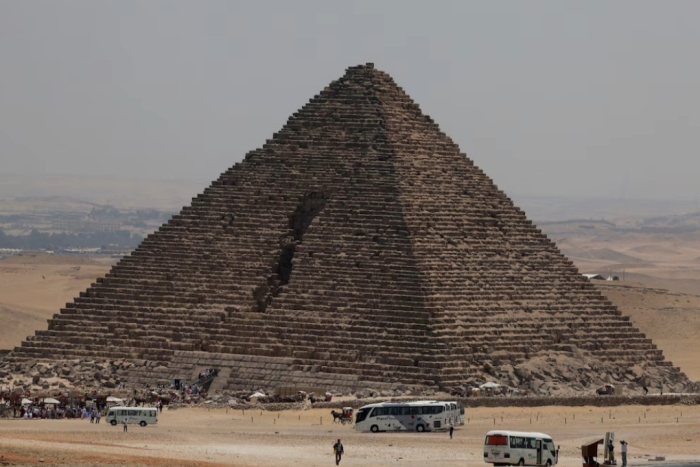 Turistas se reúnen frente a la pirámide de Menkaura, donde nuevos estudios revelaron posibles cavidades que podrían indicar una entrada aún desconocida en la estructura más pequeña de Giza.